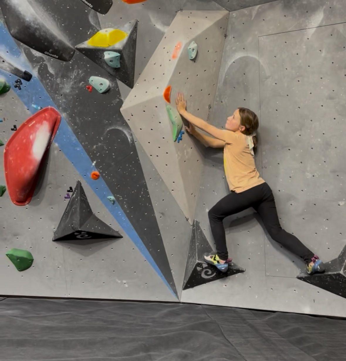 Jeune grimpeuse en cours sur un mur de bloc